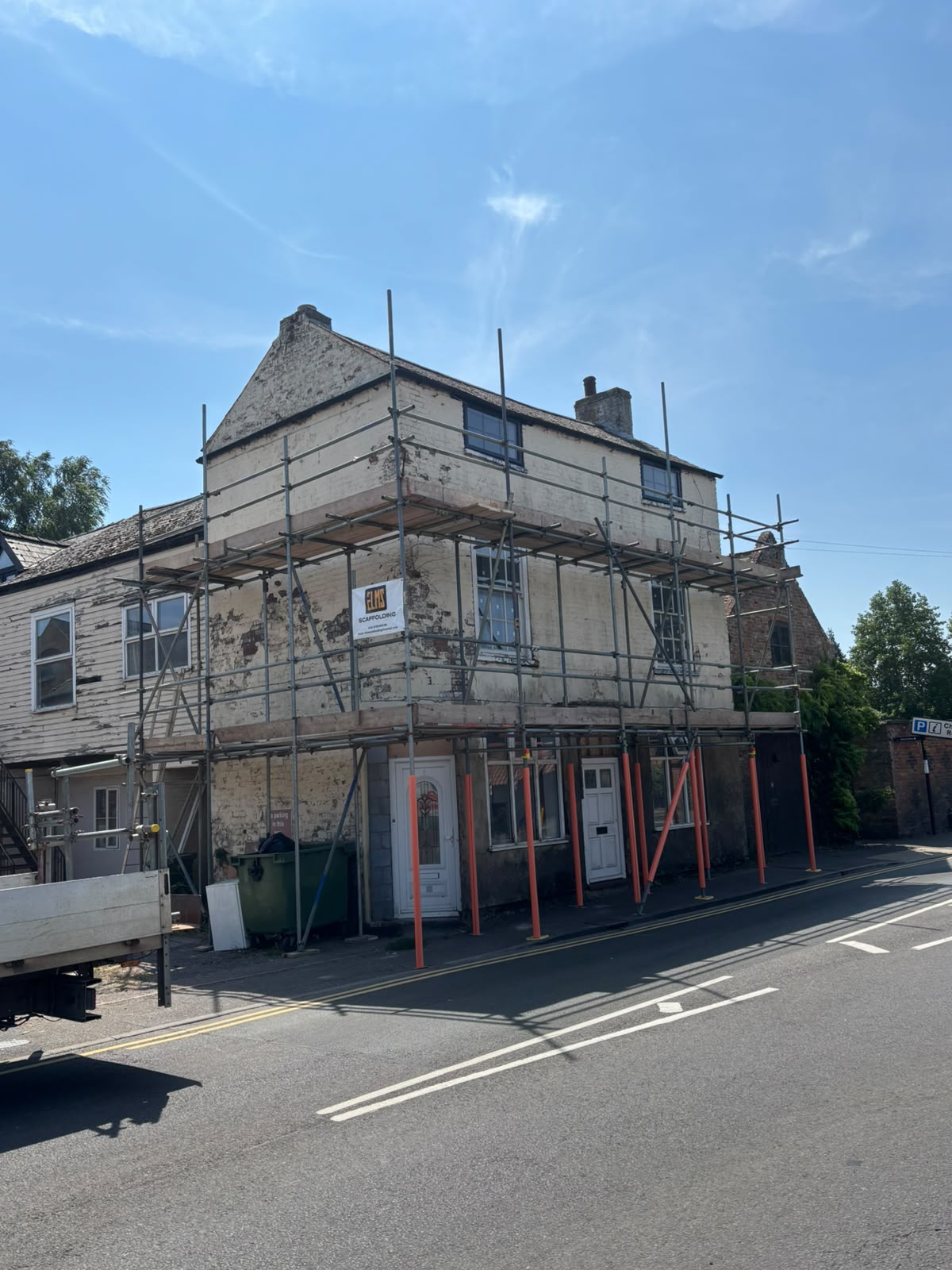 Period corner building with roadside scaffold and Elms Scaffolding banner